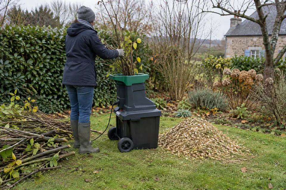 Broyeur de végétaux utilisé en automne pour réduire des branches de taille en copeaux au jardin